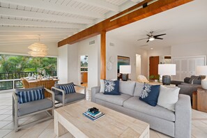 A modern living room with a sofa, armchairs, and a coffee table. There is a dining area with a table and chairs. The room has a balcony with a railing. - 2BR, 3BA Oceanfront retreat with pool, balcony, and beach access-Kapalua Bay Villas 23B3 (Lahaina)