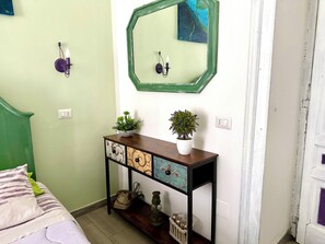 A bedroom with a bed, a bedside table with a telephone, a mirror, and a wall-mounted light fixture. - L'altra porta (Naples)