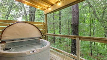 Un bain à remous avec une terrasse en bois et vue sur une forêt.