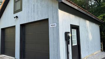 Un bâtiment doté de deux portes de garage, d’une porte avec une fenêtre et d’une enseigne sur laquelle on peut lire « PERCH ».