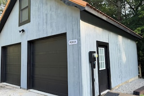 A building with two garage doors, a door with a window, and a sign that reads 'PERCH.' - Pond View & Hot Tub! 'The Perch' in Hocking Hills (Rockbridge)