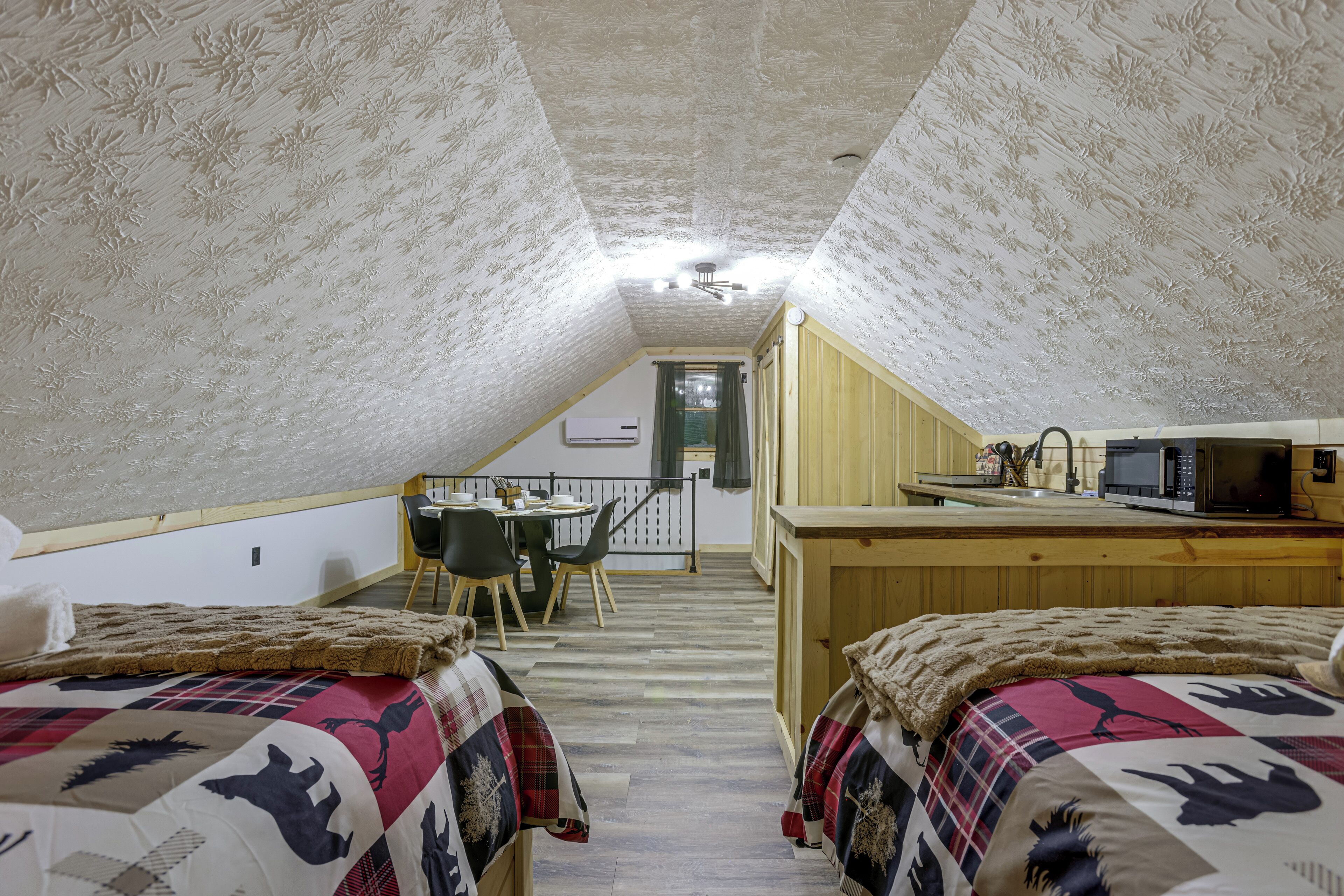Une chambre confortable située dans les combles, avec deux lits, une table à manger et un coin cuisine.