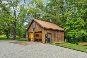 A wooden cabin with a gabled roof, a front entrance, and a gravel driveway.