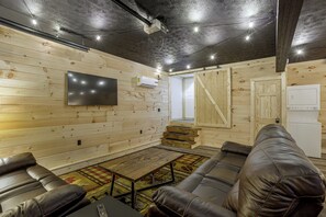 Una habitación acogedora con televisión de pantalla plana en la pared, una puerta de madera y un electrodoméstico blanco.