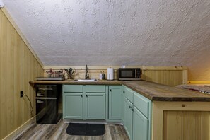 A compact kitchen with a microwave, sink, and a built-in refrigerator.