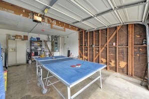 Una mesa de ping pong en un garaje con pared de madera y puerta de metal.
