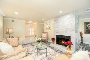 Una sala de estar con chimenea, un sofá, una mesa de centro y una lámpara.