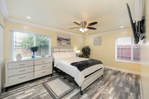 A bedroom with a bed, nightstand, dresser, ceiling fan, and two windows with blinds. - Near Golden 1 Center! Modern Home w/ Ping-Pong (Sacramento)