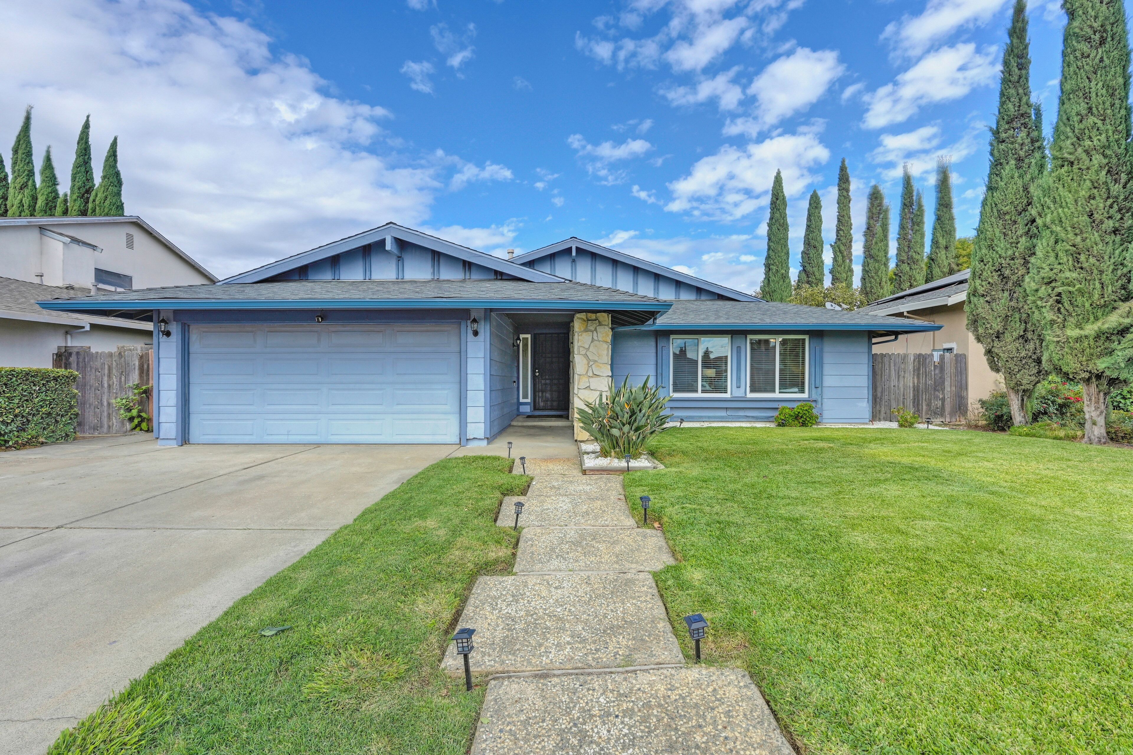 A single-story house with a blue garage, a front porch, and a well-maintained lawn.