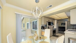A modern kitchen with stainless steel appliances, a dining area with a glass table and chairs, and a sliding glass door leading to a patio. - Near Golden 1 Center! Modern Home w/ Ping-Pong (Sacramento)