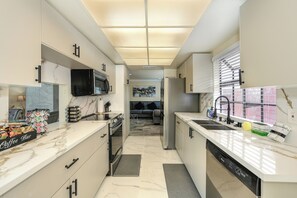 A modern kitchen with a central island, built-in appliances, and a view into the living area. - Near Golden 1 Center! Modern Home w/ Ping-Pong (Sacramento)