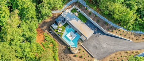Vista aérea de una propiedad con piscina, bañera de hidromasaje y zona de patio techada.
