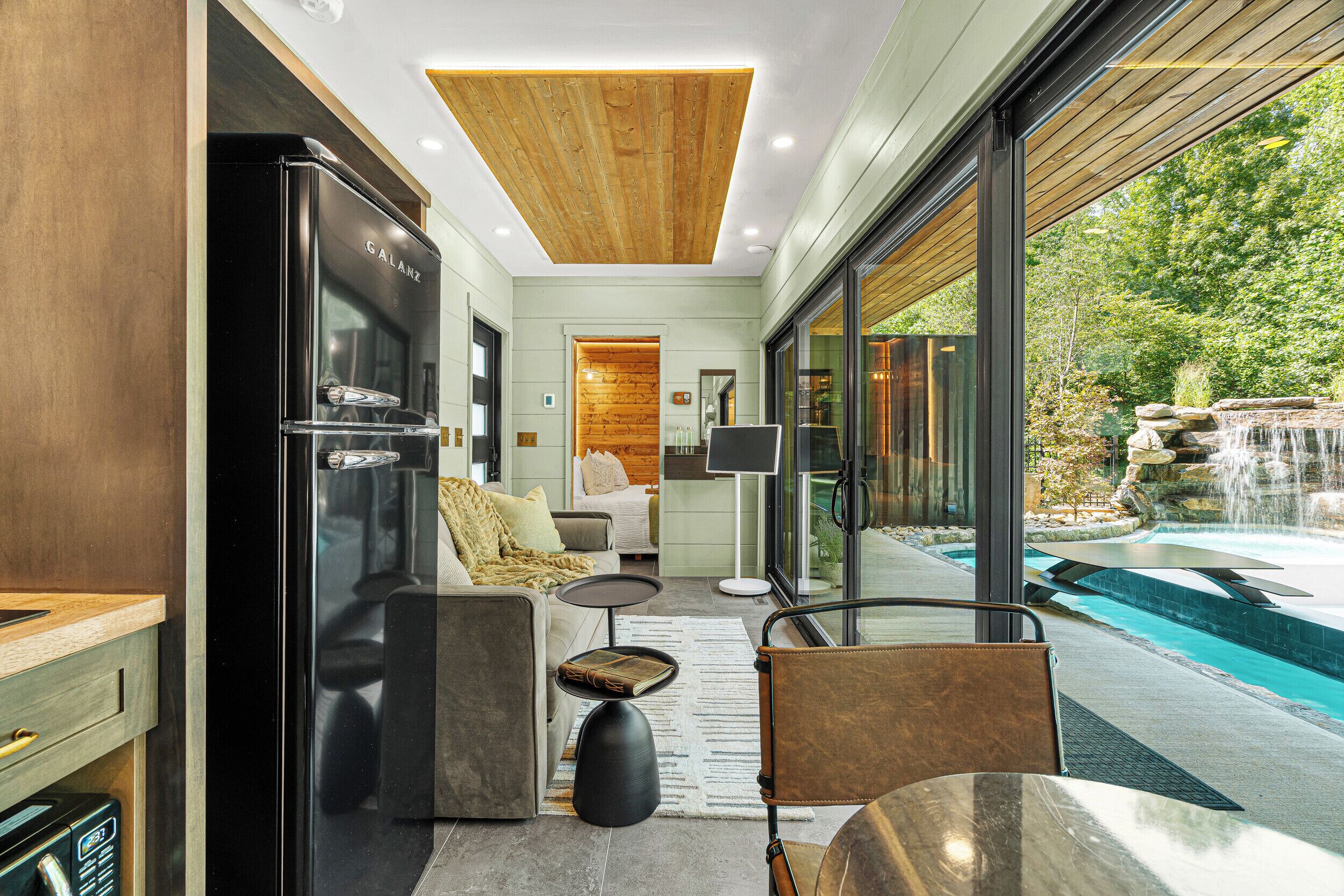 A modern interior with a kitchen, seating area, and a view of an outdoor swimming pool.
