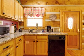 A kitchen with wooden cabinets, a granite countertop, a coffee maker, a toaster, and a dishwasher. - 1 Mi to Dollywood! Hot Tub Hideaway in Smokies (Sevierville)