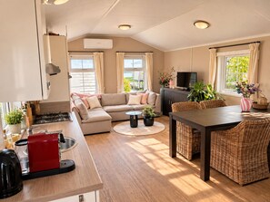 A modern living space with a kitchen, a sofa, a dining area, and a TV. - Detached chalet with a hardwood terrace in the car-free heart of Giethoorn. Features a fully equipped kitchen with a dishwasher, a comfortable bedroom with a double bed, and a private washing machine in the storage room. The perfect base for a relaxi (Giethoorn)