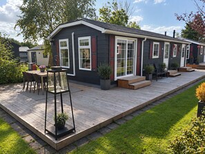 A modern house with a deck, outdoor seating, and potted plants. - Detached chalet with a hardwood terrace in the car-free heart of Giethoorn. Features a fully equipped kitchen with a dishwasher, a comfortable bedroom with a double bed, and a private washing machine in the storage room. The perfect base for a relaxi (Giethoorn)