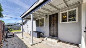 A residential property with a covered porch, a door with a metal gate, and a small outdoor seating area.