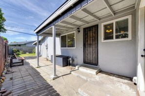 Ein Wohnhaus mit überdachter Veranda, einer Tür mit Metallgitter und einer kleinen Sitzgelegenheit im Freien.
