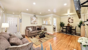 A living room with a sofa, coffee table, and a dining area with chairs and a table.