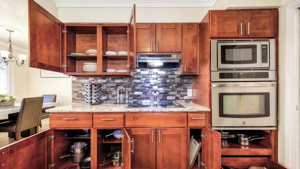A kitchen with wooden cabinets, a tiled backsplash, stainless steel appliances, and a built-in oven.