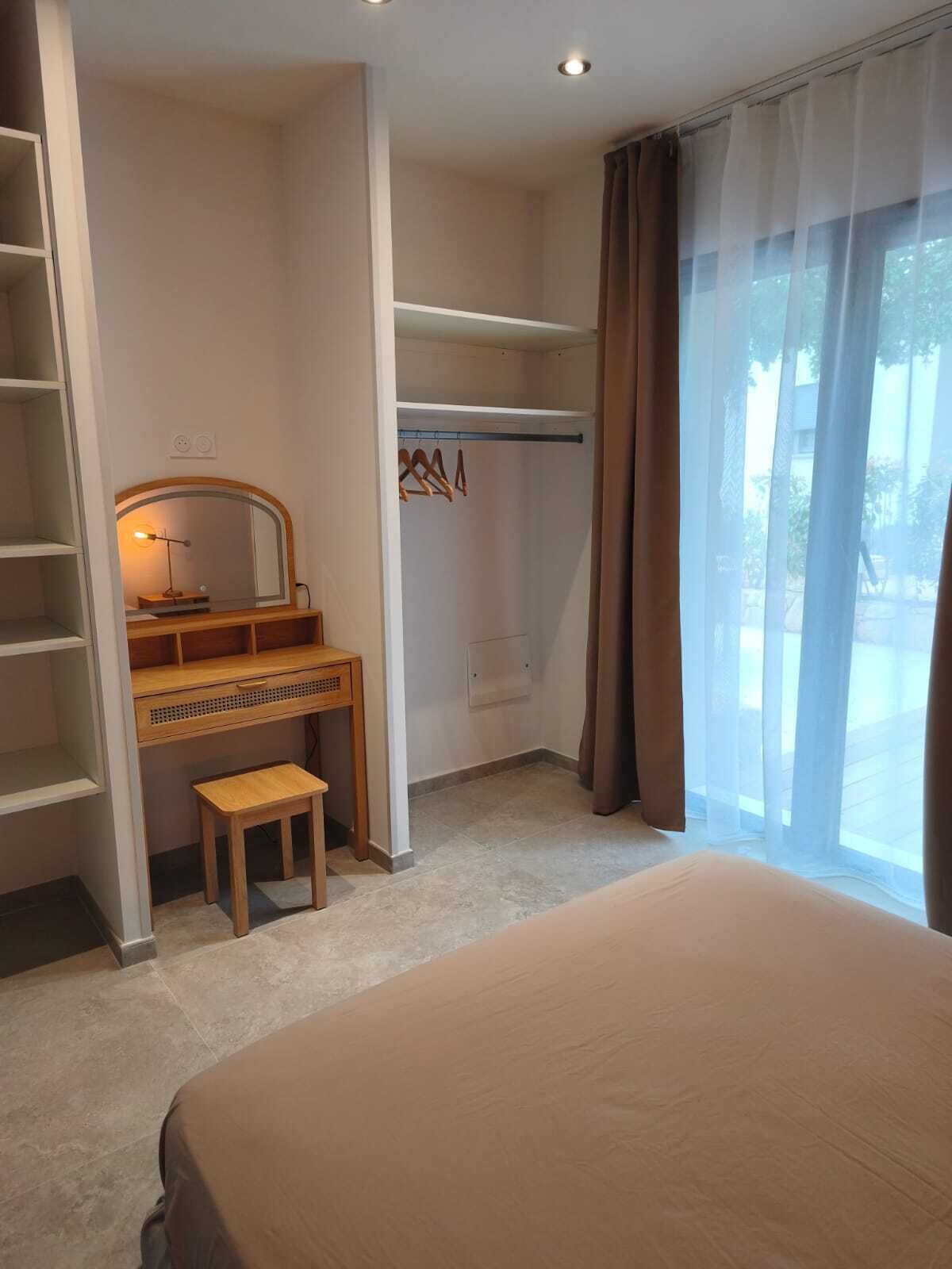 A bedroom with a bed, a desk with a chair, a wardrobe, and a mirror.