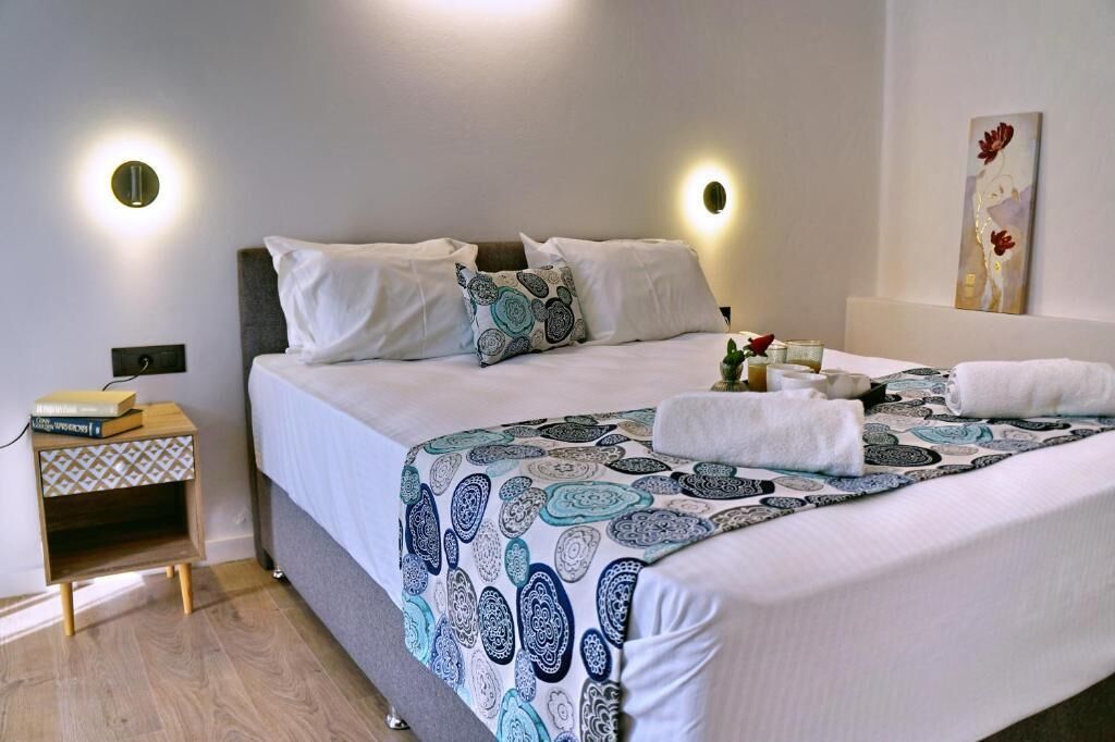 A neatly made bed with a patterned bedspread, a bedside table with a lamp, and a wall-mounted artwork.