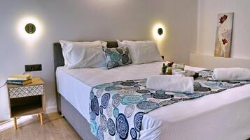 A neatly made bed with a patterned bedspread, a bedside table with a lamp, and a wall-mounted artwork.