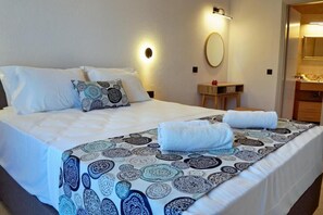 A hotel room with a bed, a bedside table, a mirror, and a bathroom visible through an open door.