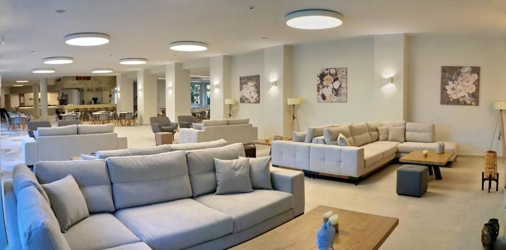 Un amplio salón con varios sofás, una mesa de centro y lámparas de pared.