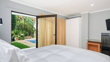 Een slaapkamer met een groot bed, een schuifdeur naar een balkon en een aan de muur bevestigde televisie.