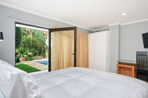 Een slaapkamer met een groot bed, een schuifdeur naar een balkon en een aan de muur bevestigde televisie.