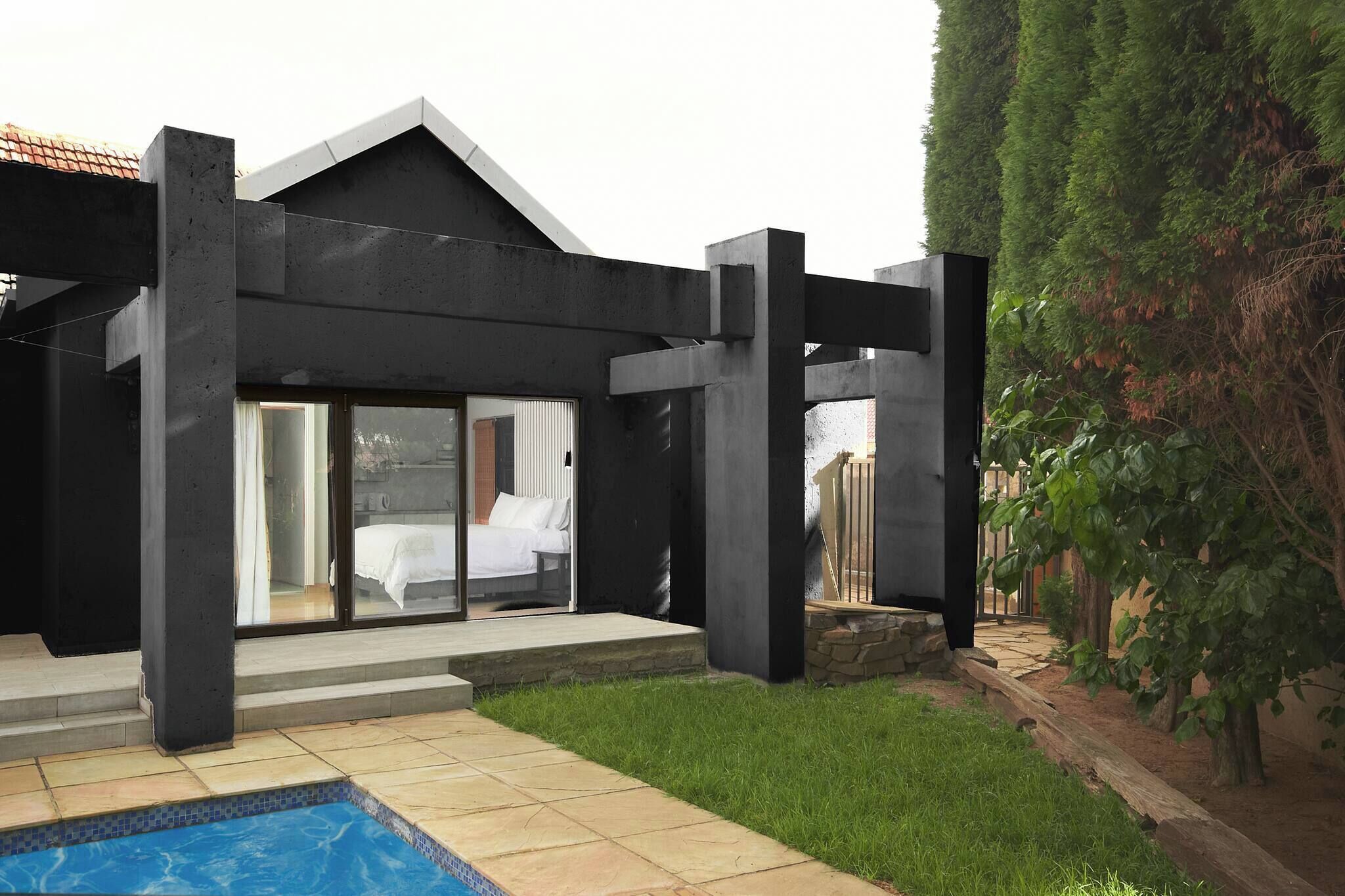 Una casa moderna con piscina, amplios ventanales y un camino de piedra.