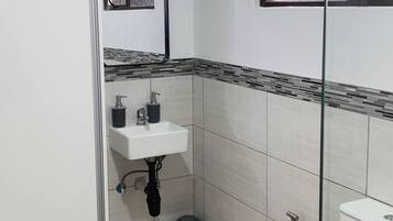 A small, clean bathroom with a toilet, sink, and shower.