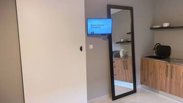 A modern kitchen with a wooden cabinet, a microwave, and a coffee maker on the counter.