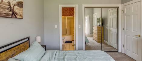 A bedroom with a bed, a nightstand, a lamp, and a painting on the wall.