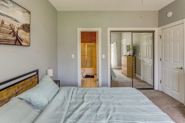 A bedroom with a bed, a nightstand, a lamp, and a painting on the wall. - 6 Pools, Golf Course! Myrtle Beach Family Condo (Myrtle Beach)