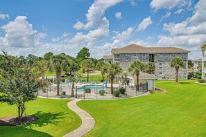 A residential area with a swimming pool, stone building, and well-maintained lawn. - 6 Pools, Golf Course! Myrtle Beach Family Condo (Myrtle Beach)