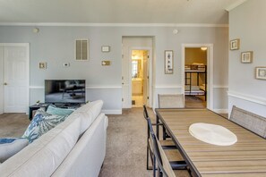 Ein Wohnzimmer mit Fernseher, Sofa und Esstisch.