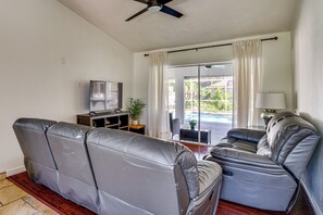 A living room with a sofa, a television, a plant, and a view of a swimming pool. - 2 Mi to Six Mile Preserve! Family Getaway w/ Pool (Fort Myers)