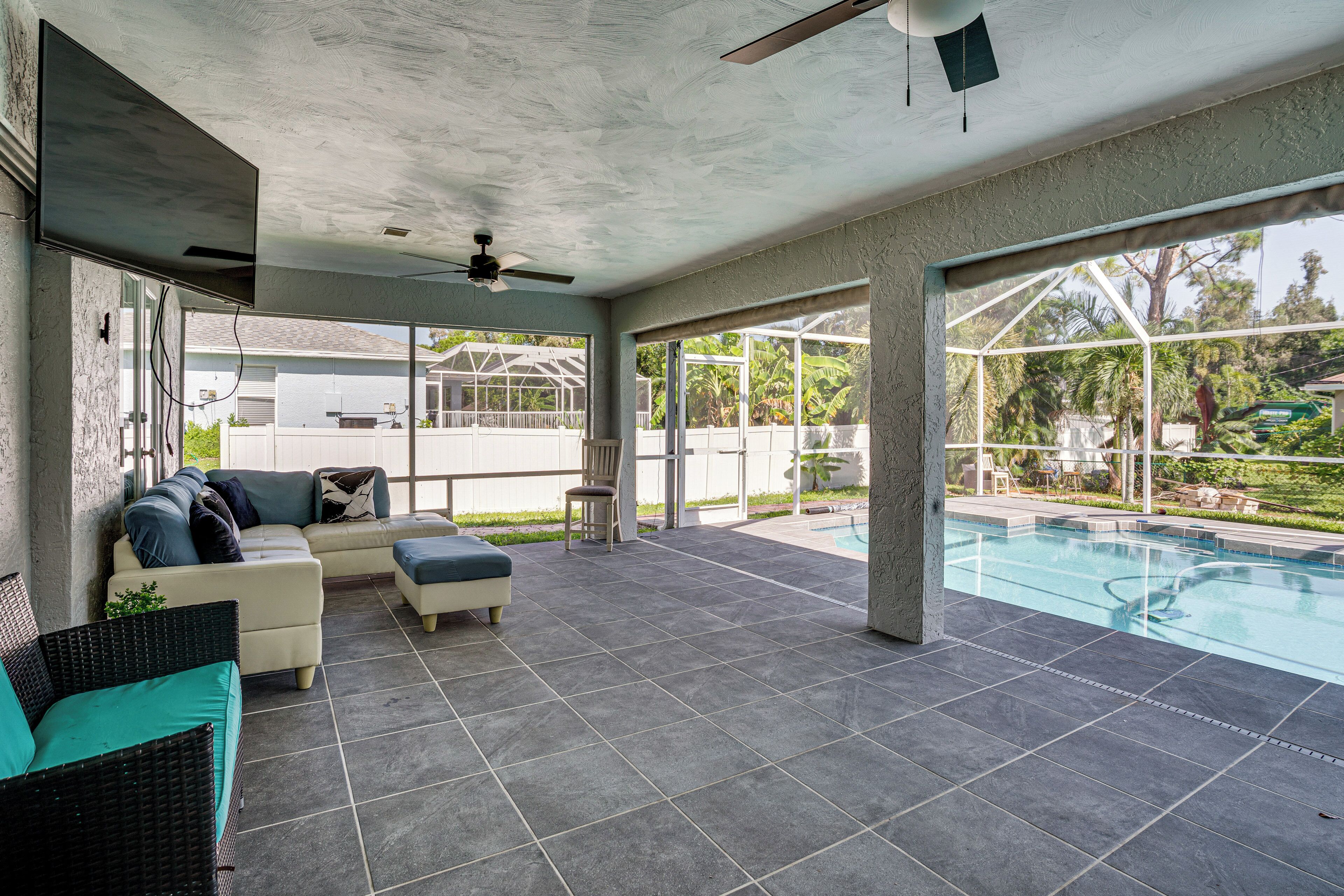 A covered outdoor area with a pool, seating, and a ceiling fan.