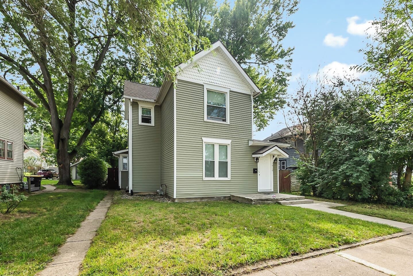 A two-story residential house with a front yard, a driveway, and a small front porch.