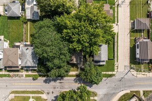Eine Vogelperspektive eines Wohngebiets mit Häusern, einer Straße und einem großen Baum.