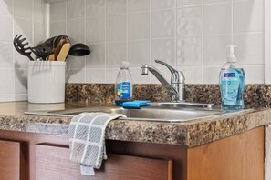 Eine Küche mit einer Granit-Arbeitsplatte, einer Edelstahl-Spüle, einer Flasche Geschirrspülmittel, einer Handseifenflasche und einem Handtuch.