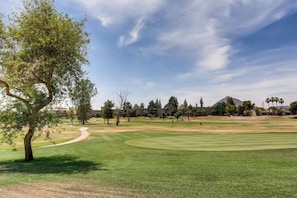 A golf course with a clear sky, a path leading to the tee, and a flag on the green. - Golf Course Condo, Mountain Views, Old Town (Scottsdale)