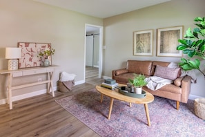 A living room with a sofa, coffee table, and artwork on the walls.