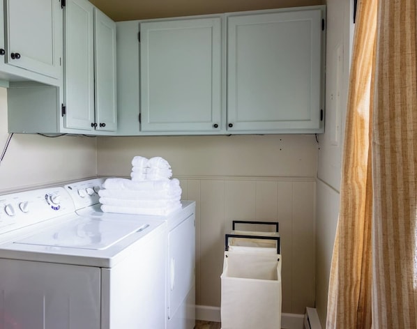 A laundry area with a washing machine, stacked towels, and a drying rack.