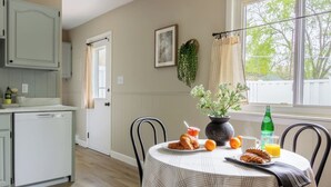 A dining area with a table set for breakfast, including croissants, oranges, and a bottle of juice.