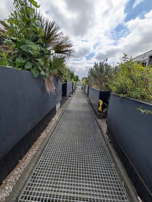 A pathway flanked by vegetation and a metal grate. - Modern 2 Bedroom House near MediaCity (Salford)