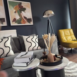 A modern living room with a grey sofa, a yellow armchair, a round coffee table, and a floor lamp. - Modern 2 Bedroom House near MediaCity (Salford)