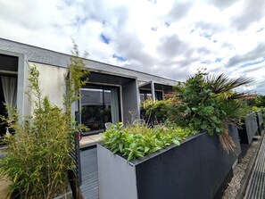 A modern building with a balcony, large windows, and a garden area with various plants. - Modern 2 Bedroom House near MediaCity (Salford)